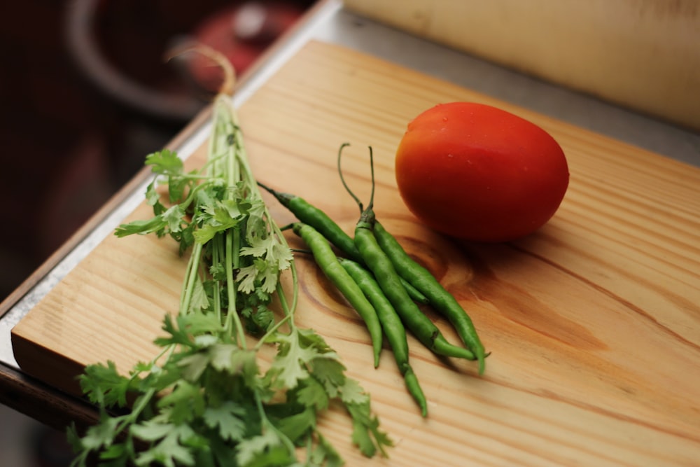 tomate rouge à côté de feuilles vertes sur une table en bois marron