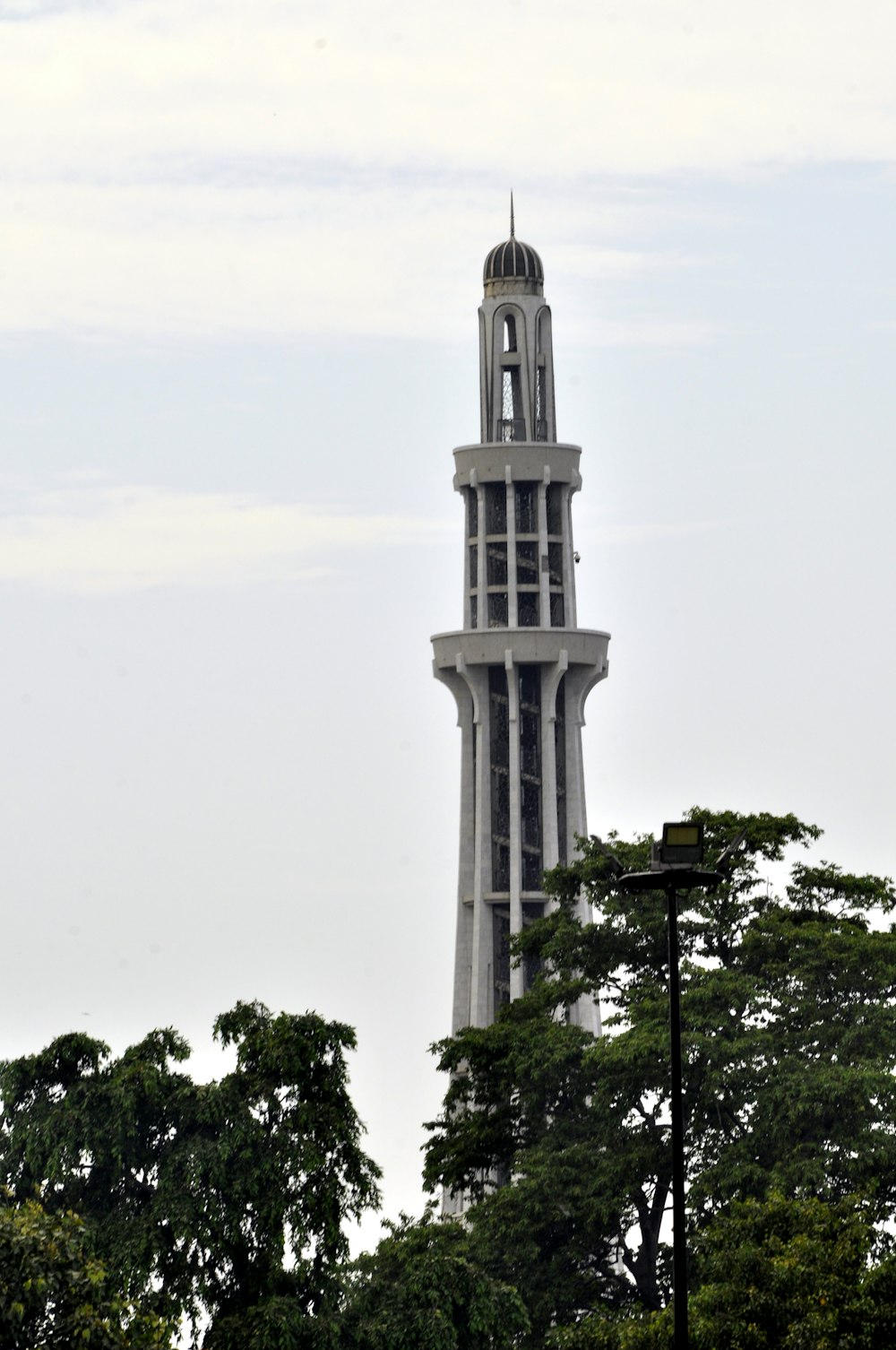 white concrete tower near green trees during daytime