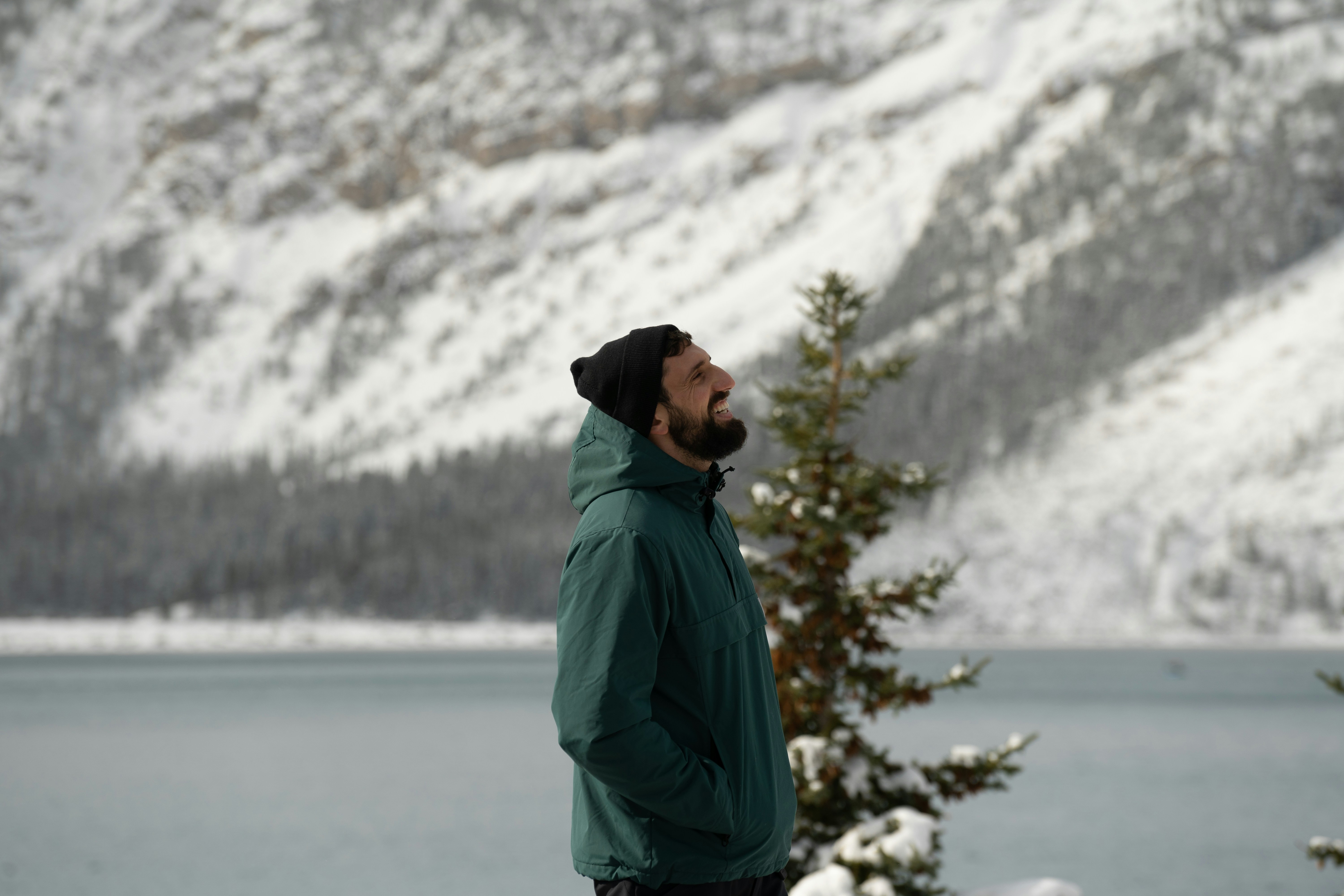 man in green jacket standing near snow covered trees during daytime