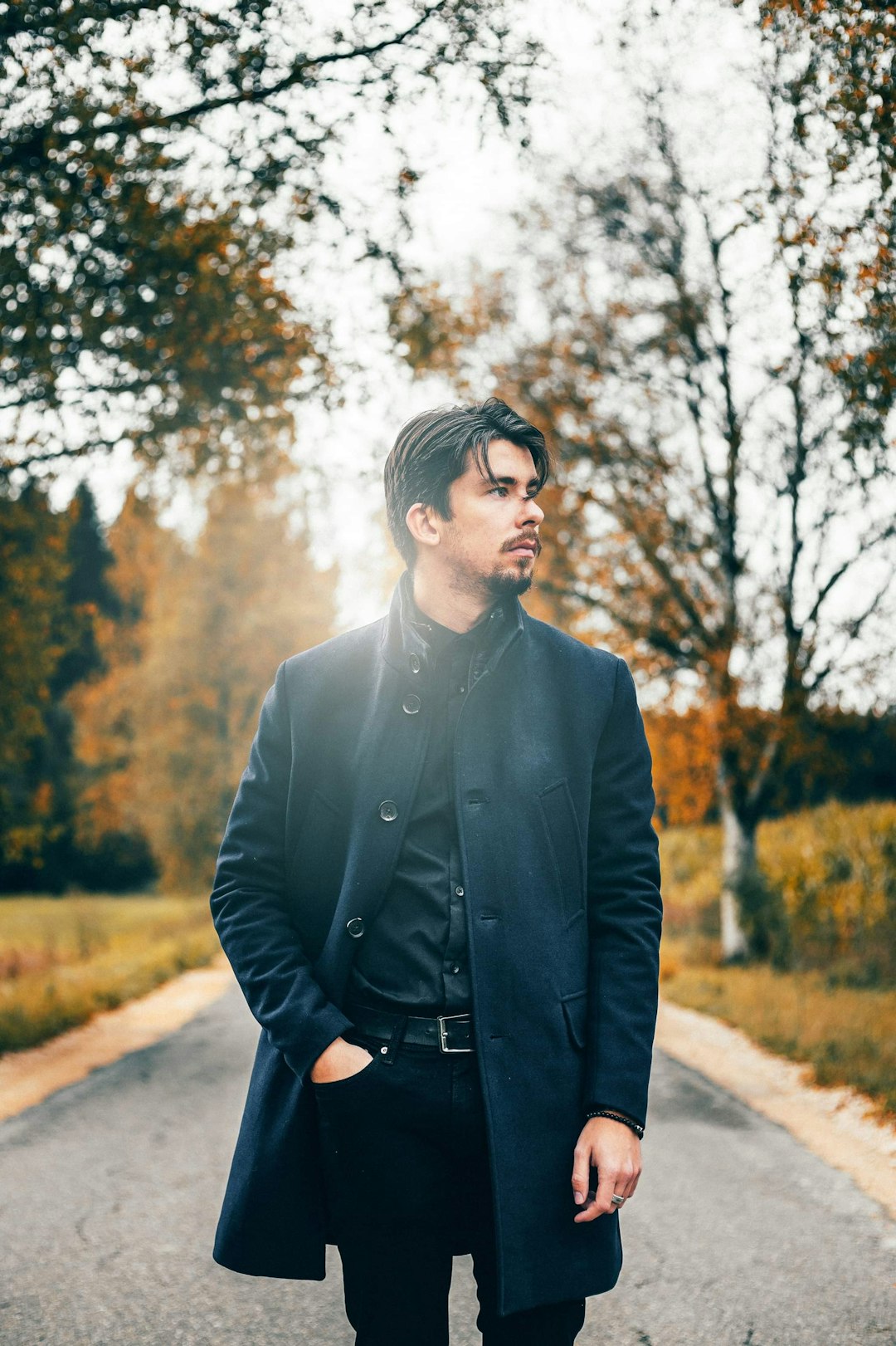 man in black suit standing near trees during daytime