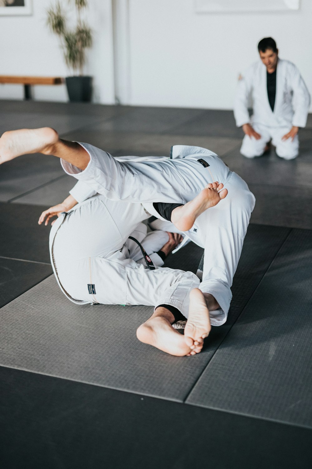 man in white t-shirt and white pants lying on black floor