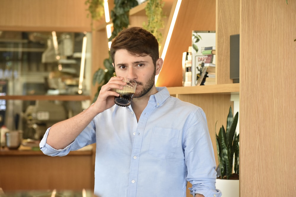 man in blue button up shirt drinking from black ceramic mug