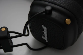 Close-up macro shot of a sleek titanium alloy in-ear monitor shell with warm gold accents against a deep black background.