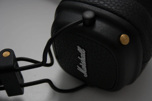 Close-up macro shot of a sleek titanium alloy in-ear monitor shell with warm gold accents against a deep black background.