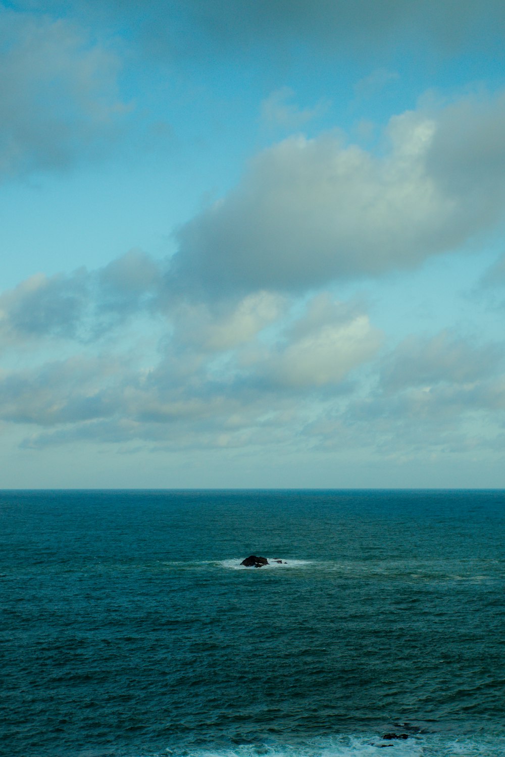 person surfing on sea under blue and white cloudy sky during daytime