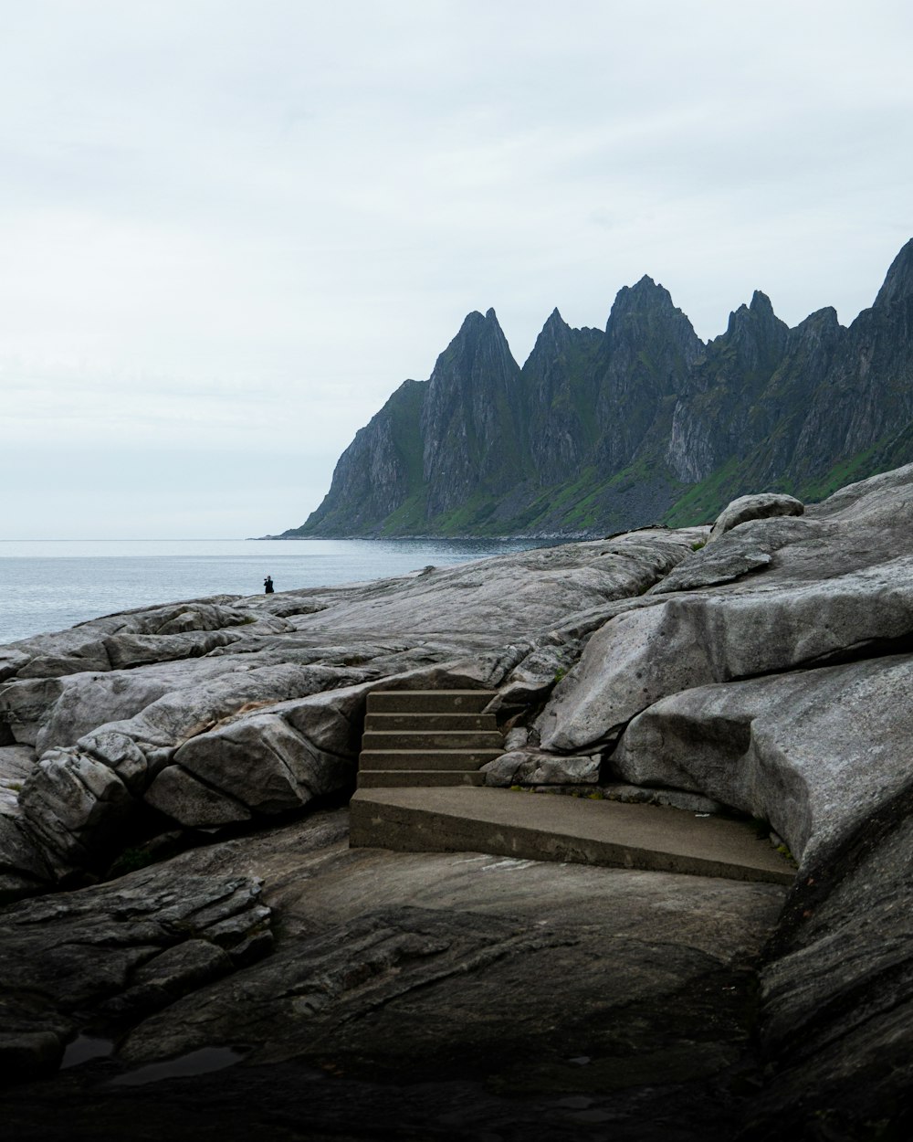 brown wooden bench on seashore near mountain during daytime