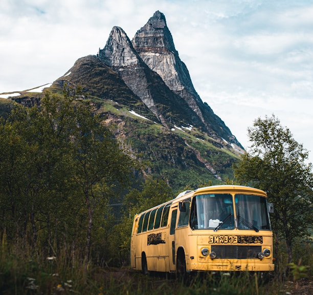 yellow bus on green grass near mountain during daytime