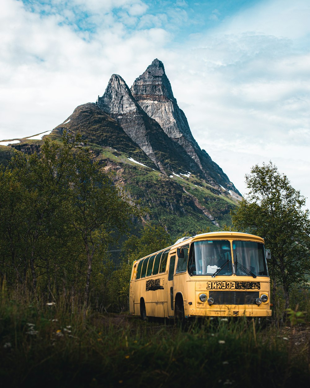 yellow bus on green grass near mountain during daytime