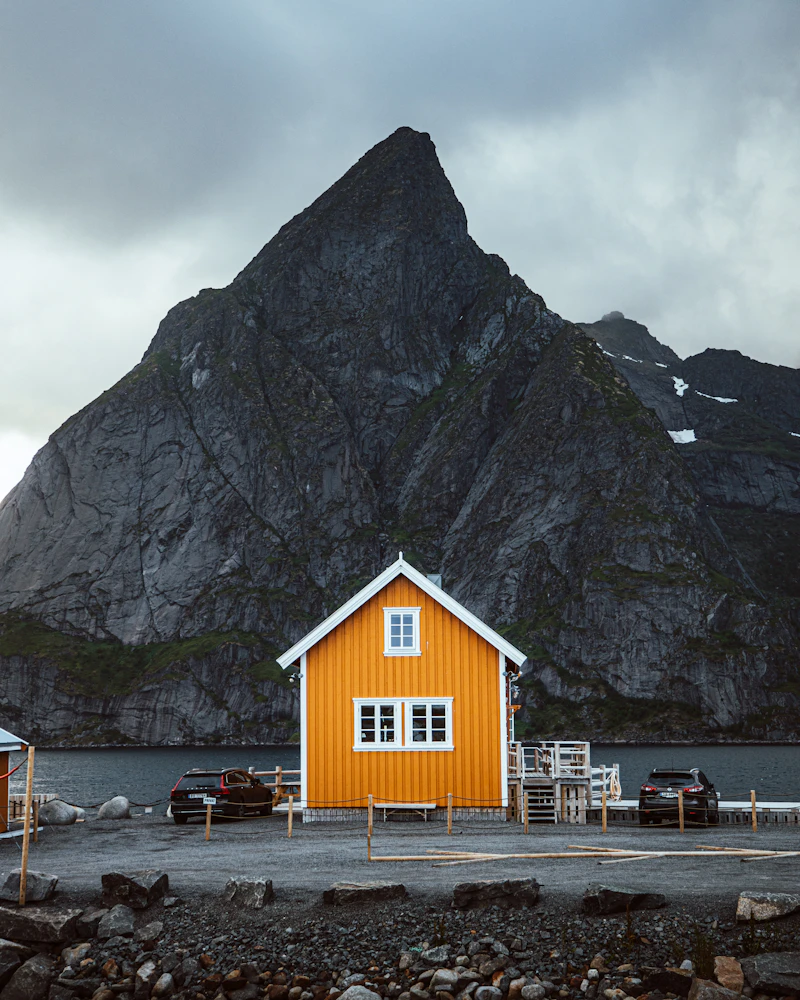 A wooden house near a grey rocky mountain