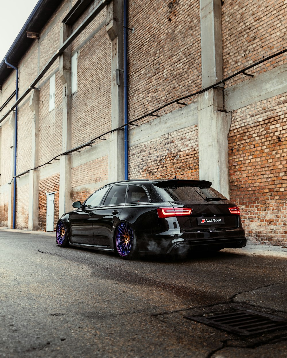 black sedan parked beside brown brick wall