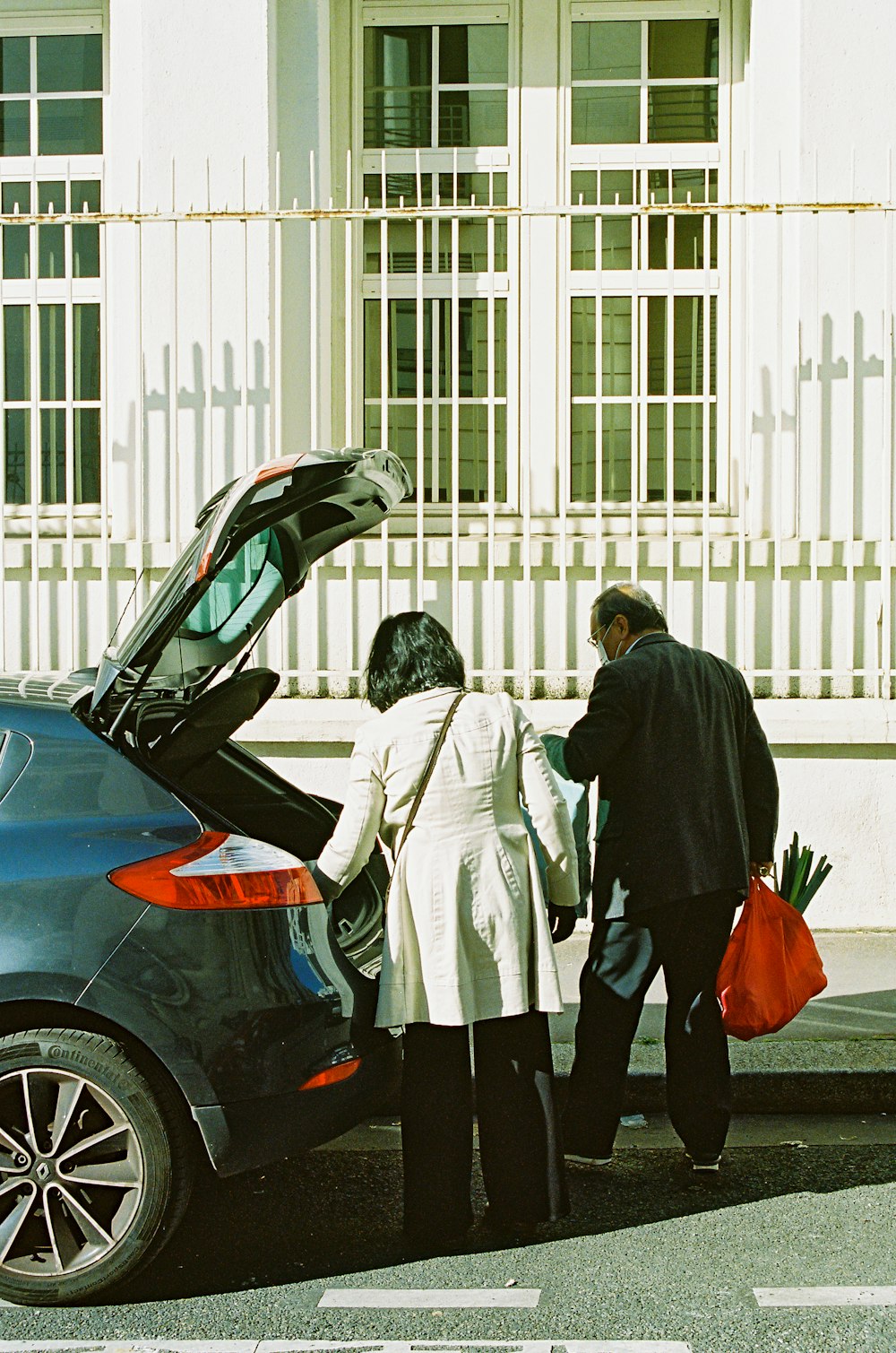 man and woman standing beside black car during daytime