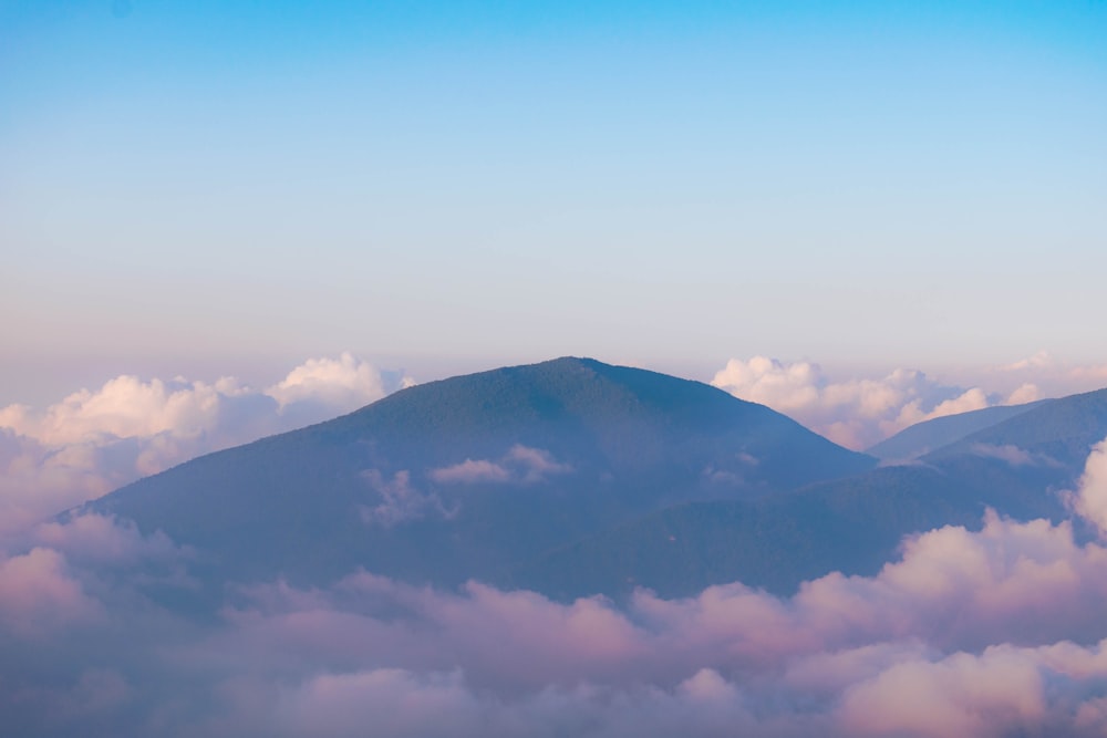 昼間の白い雲の下の緑の山