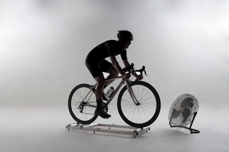 Ciclista pedalando sobre um rolo de treino ao lado de um ventilador