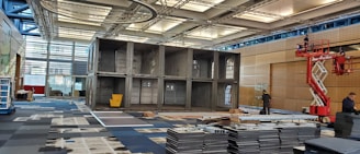 Technicians customizing a shipping container with doors and shelving inside a workshop.