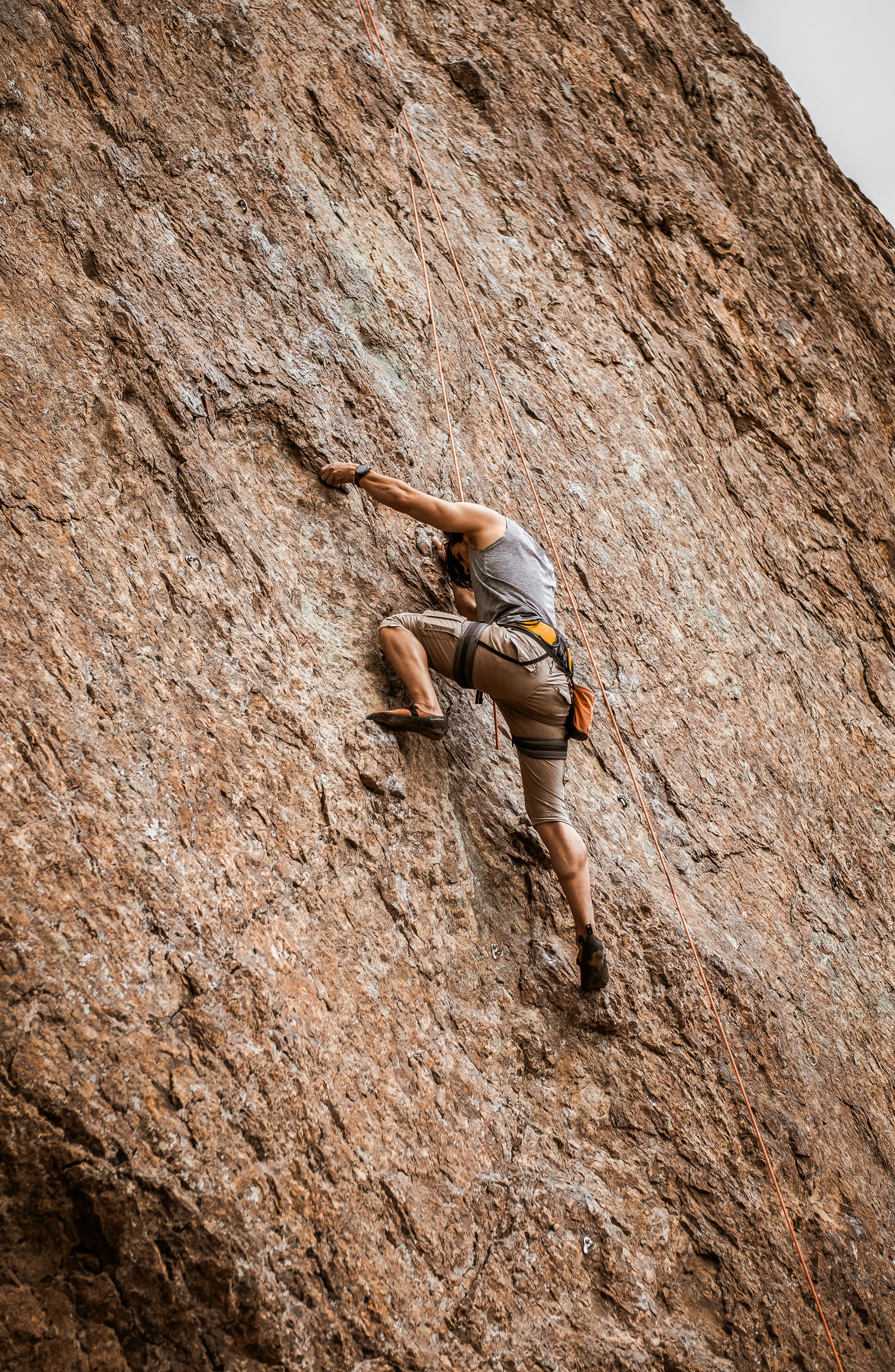 woman in gray sports bra and black shorts climbing on brown rock mountain during daytime