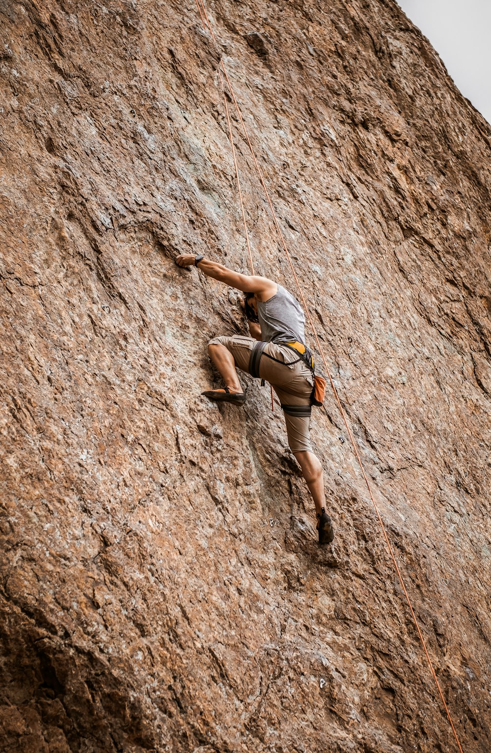 woman in gray sports bra and black shorts climbing on brown rock mountain during daytime