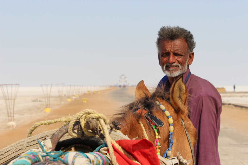 man in red sweater riding brown horse during daytime