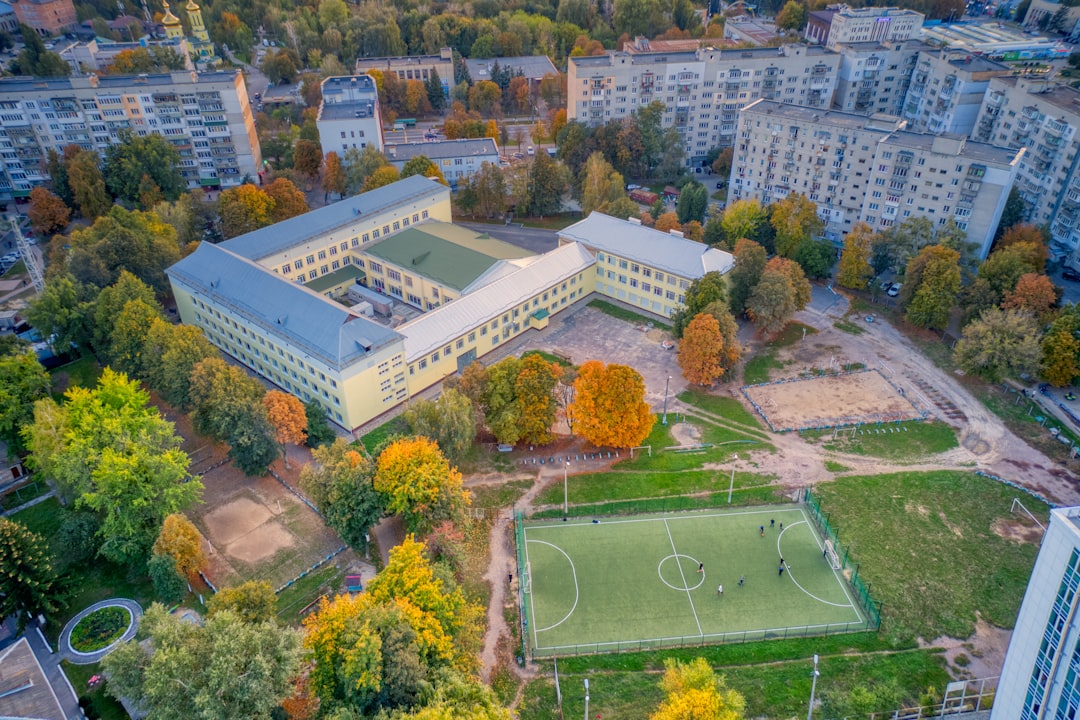 aerial view of green field surrounded by trees and white building during daytime