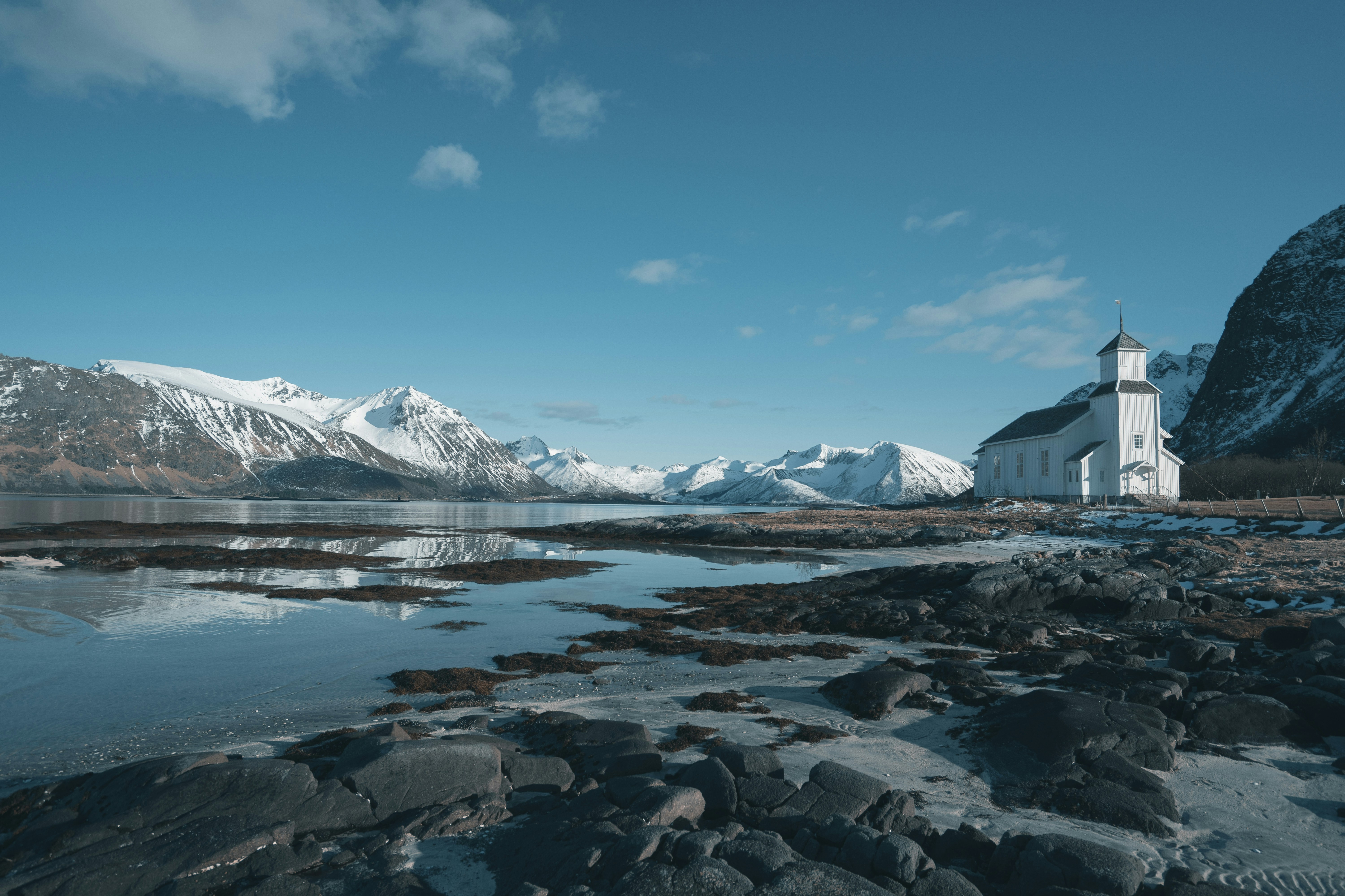 white and black mountains near body of water under blue sky during daytime