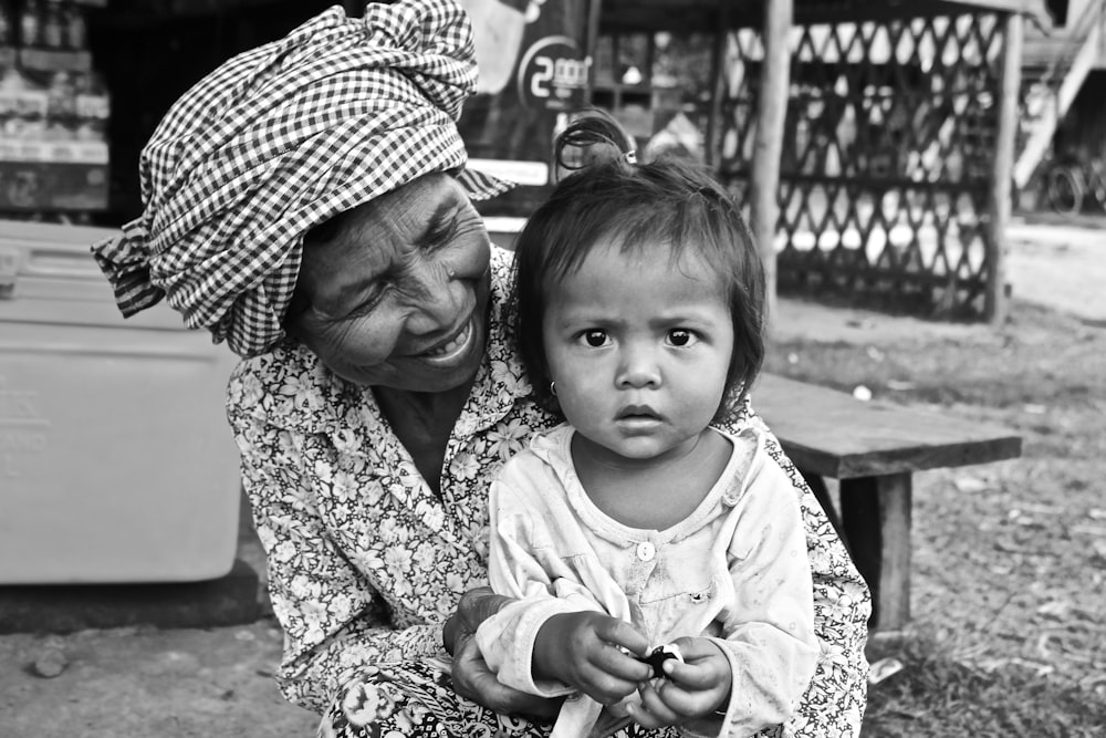 grayscale photo of woman carrying baby