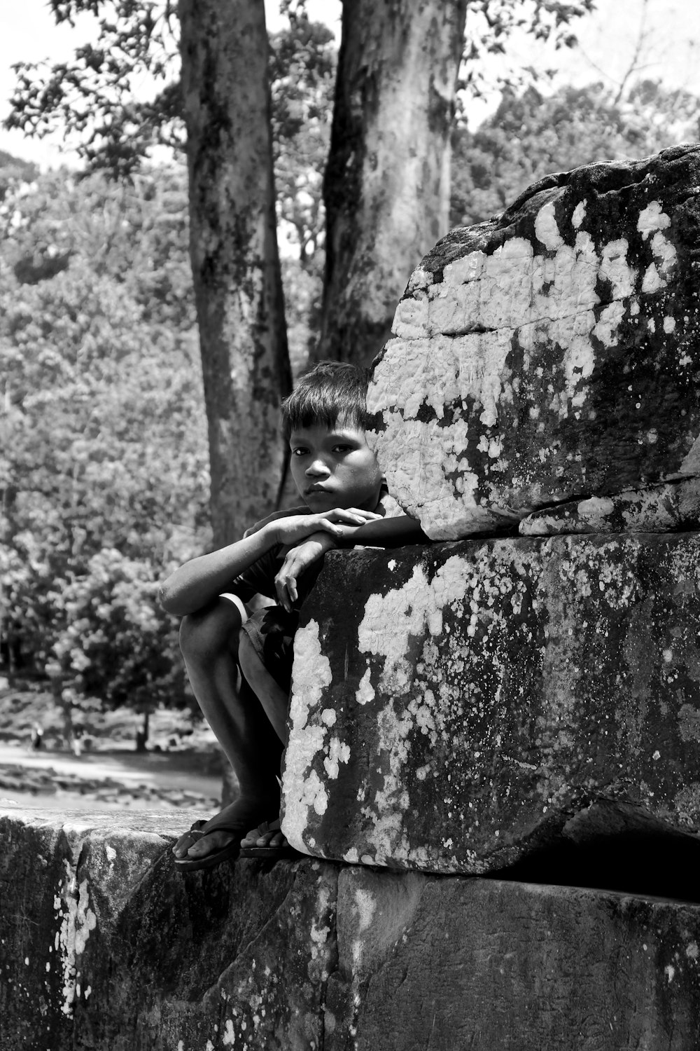 grayscale photo of woman leaning on concrete wall