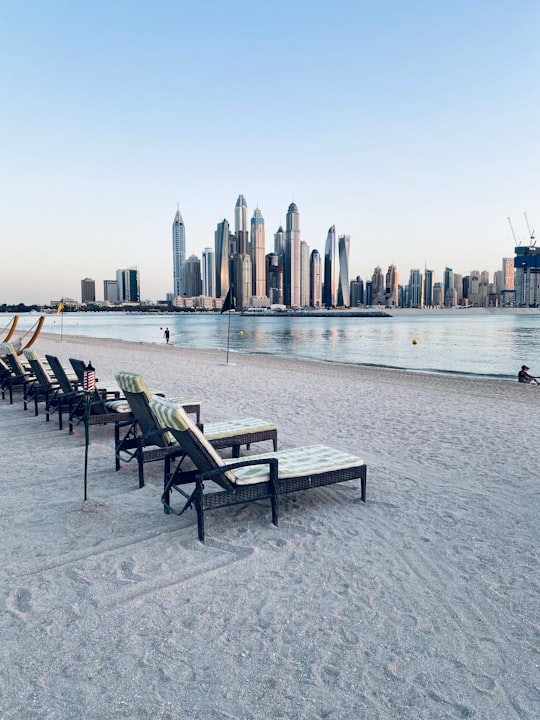 brown wooden table and chairs on gray sand near body of water during daytime in Atlantis, The Palm United Arab Emirates