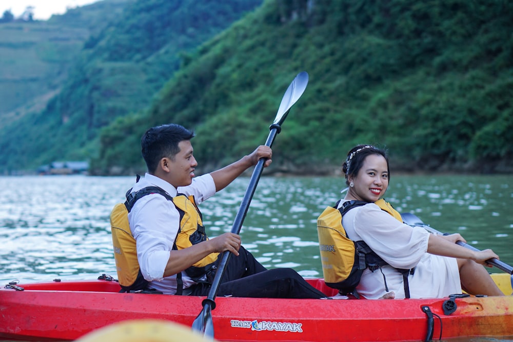 man in yellow and gray vest riding red kayak on lake during daytime