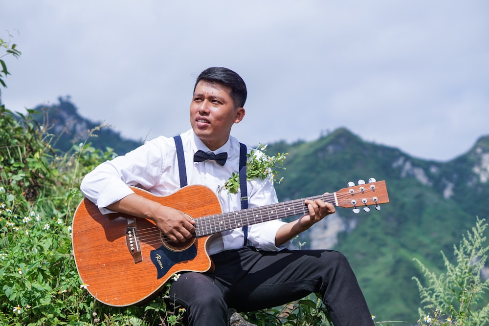 man in white dress shirt playing brown acoustic guitar