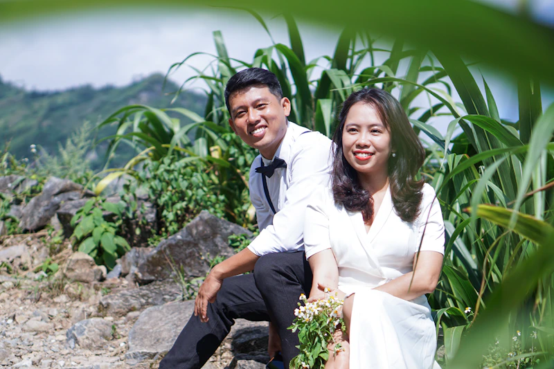 man and woman sitting on rock
