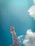 A red and white telecommunications tower extends upwards against a backdrop of a clear blue sky. Fluffy white clouds drift nearby, adding contrast to the expansive sky. The structure of the tower is detailed with metal beams and several antennae.