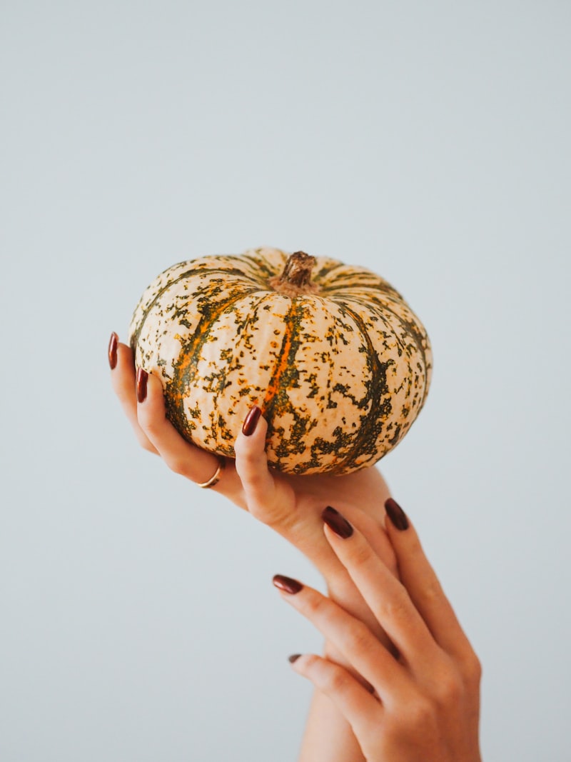 Pretty hands with Halloween manicure holding a cute pumpkin