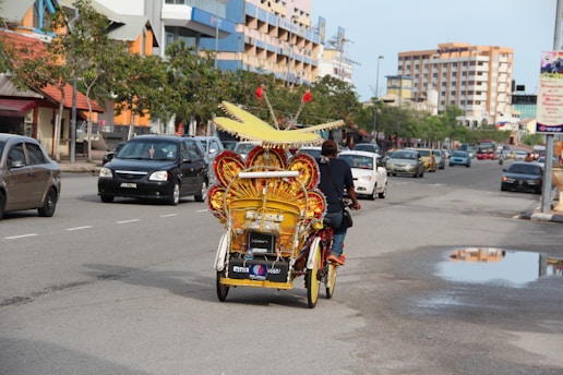 people riding on red and yellow trike on road during daytime