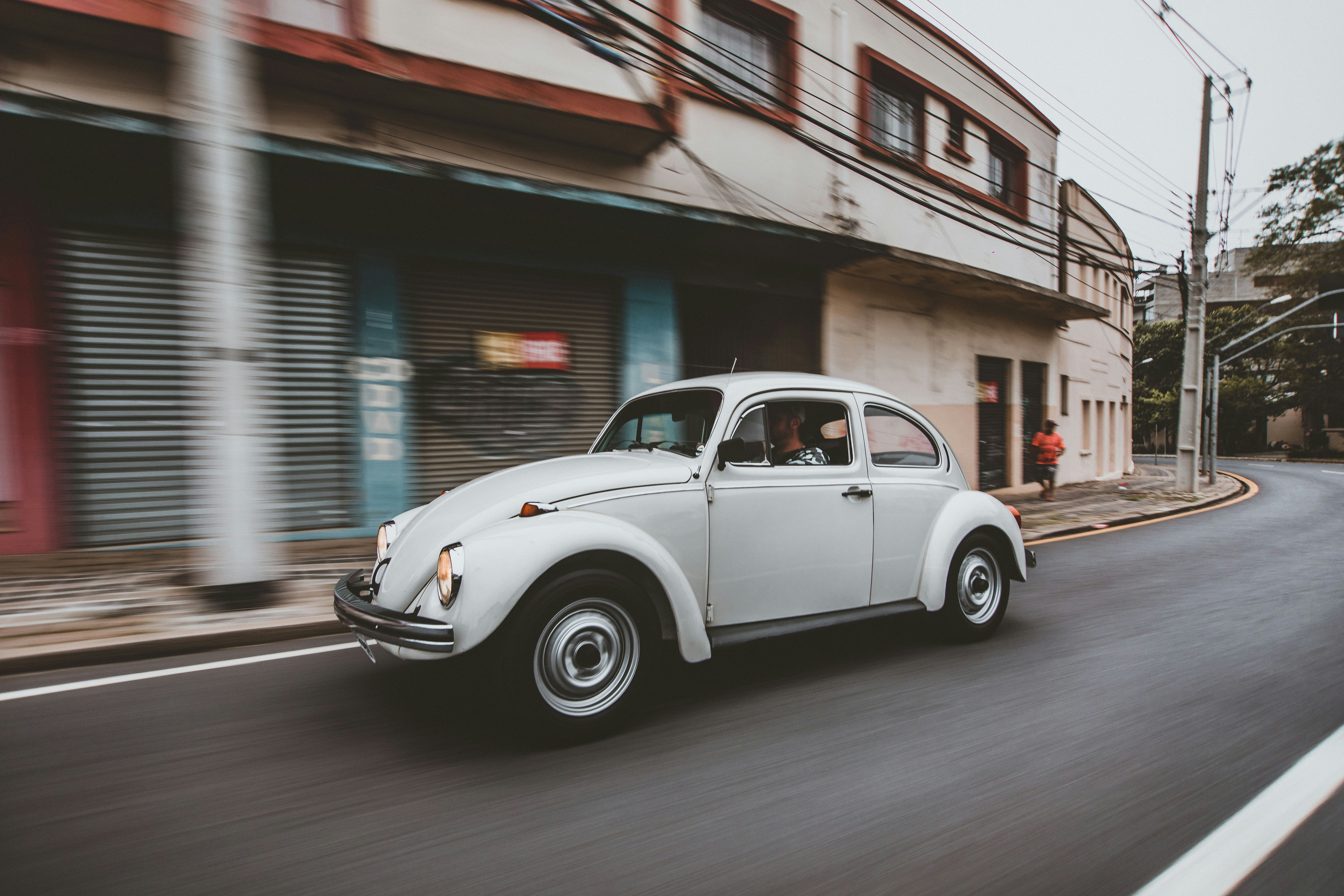 white coupe parked beside brown and white concrete building during daytime