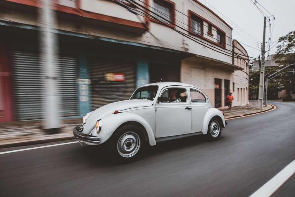 white coupe parked beside brown and white concrete building during daytime