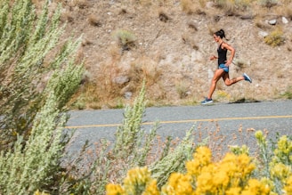 woman in black tank top running on gray asphalt road during daytime