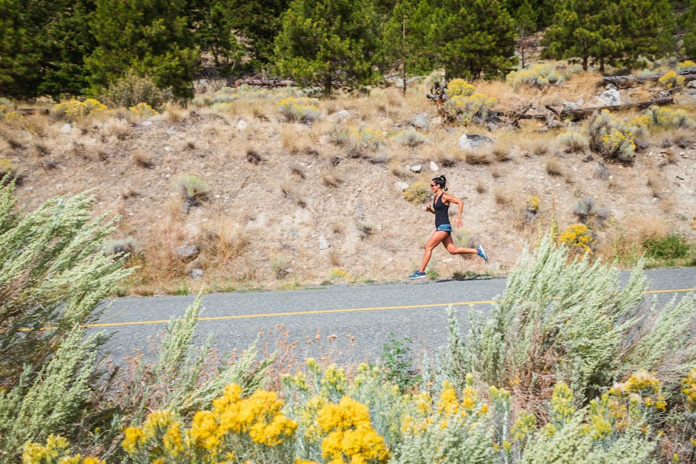 woman in red shirt and blue denim shorts running on road during daytime