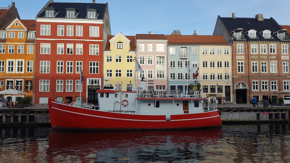 red and white boat on water near concrete buildings during daytime