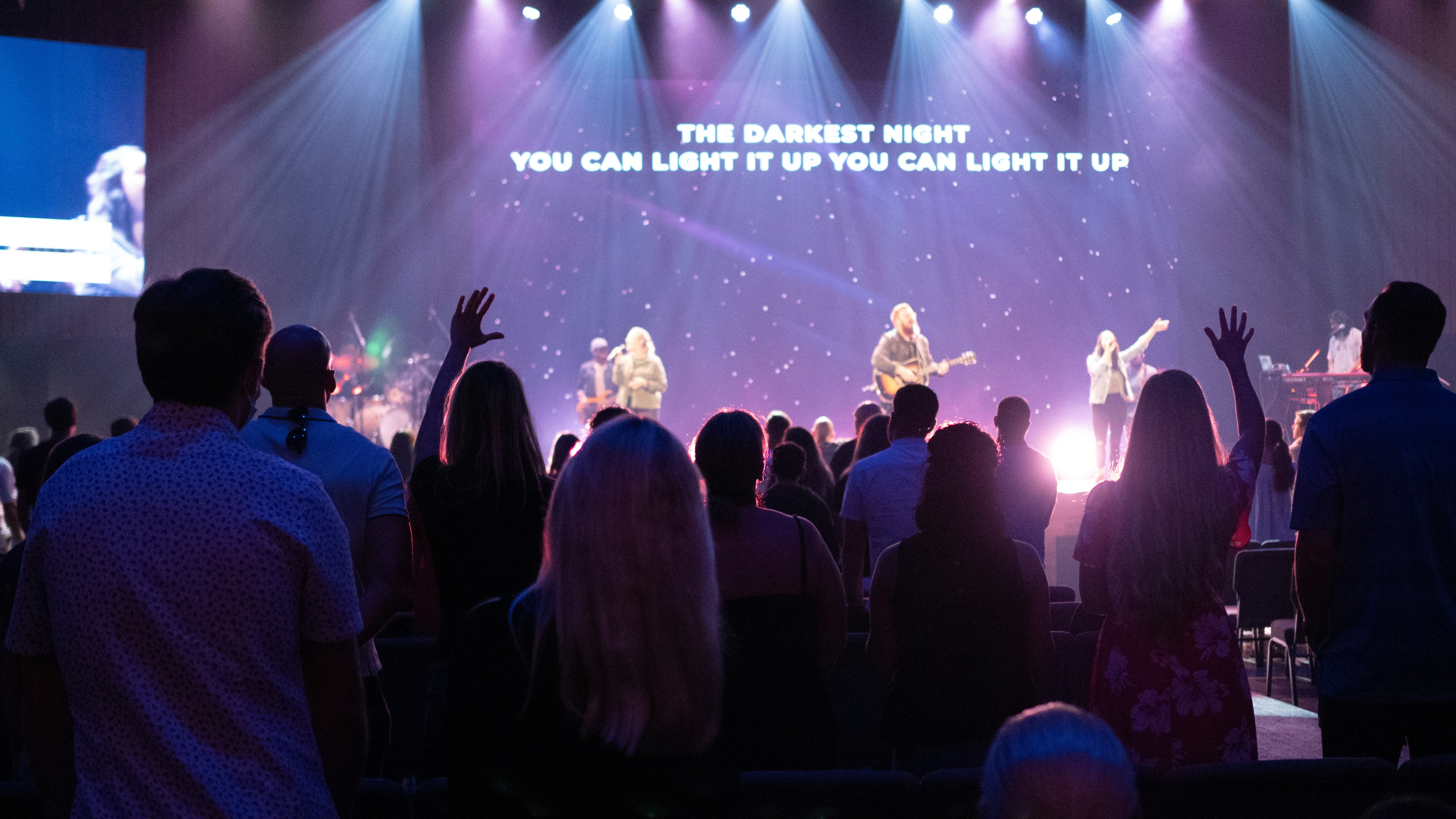 people standing on stage with lights turned on during nighttime