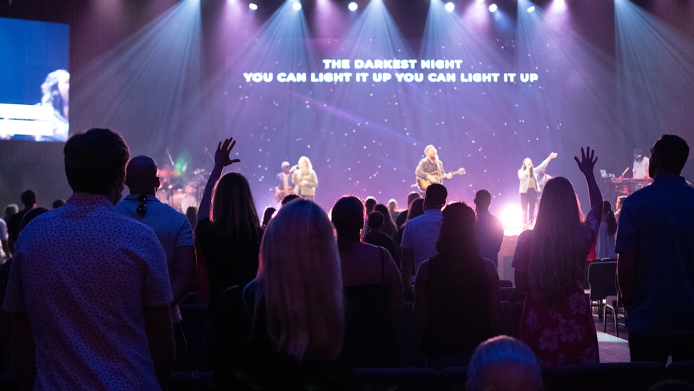 people standing on stage with lights turned on during nighttime