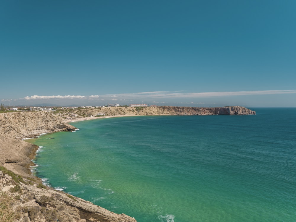 mar azul junto a la montaña marrón bajo el cielo azul durante el día