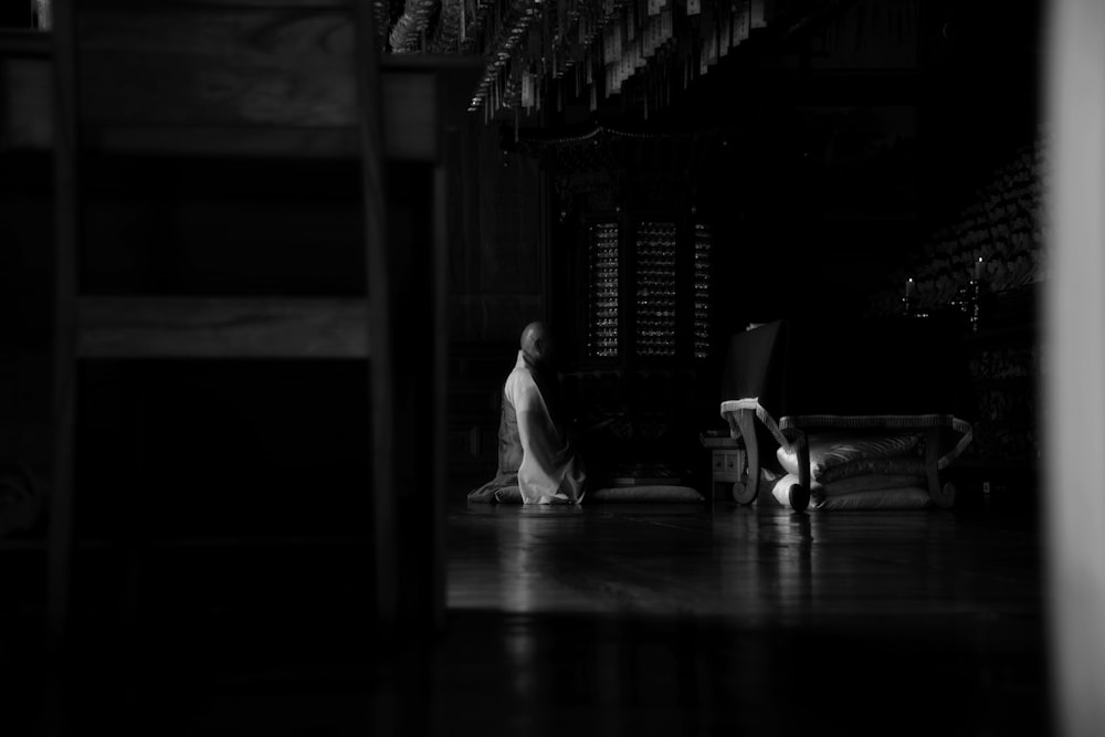 grayscale photo of man sitting on chair