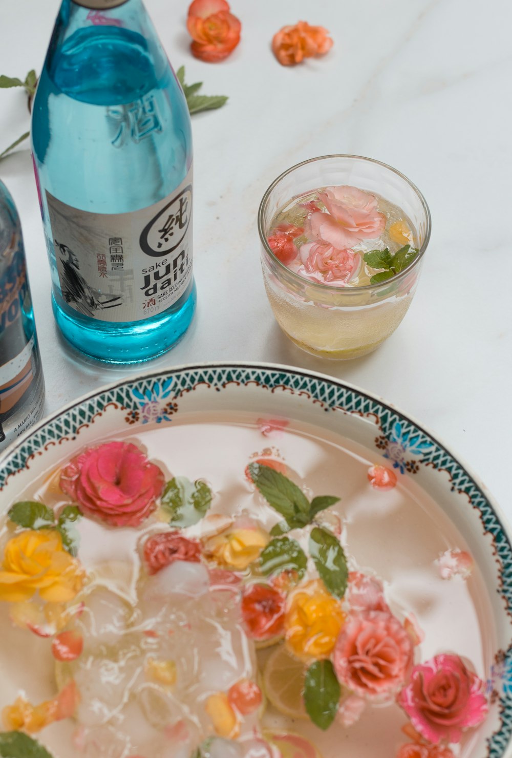a plate with flowers on it next to a bottle of alcohol