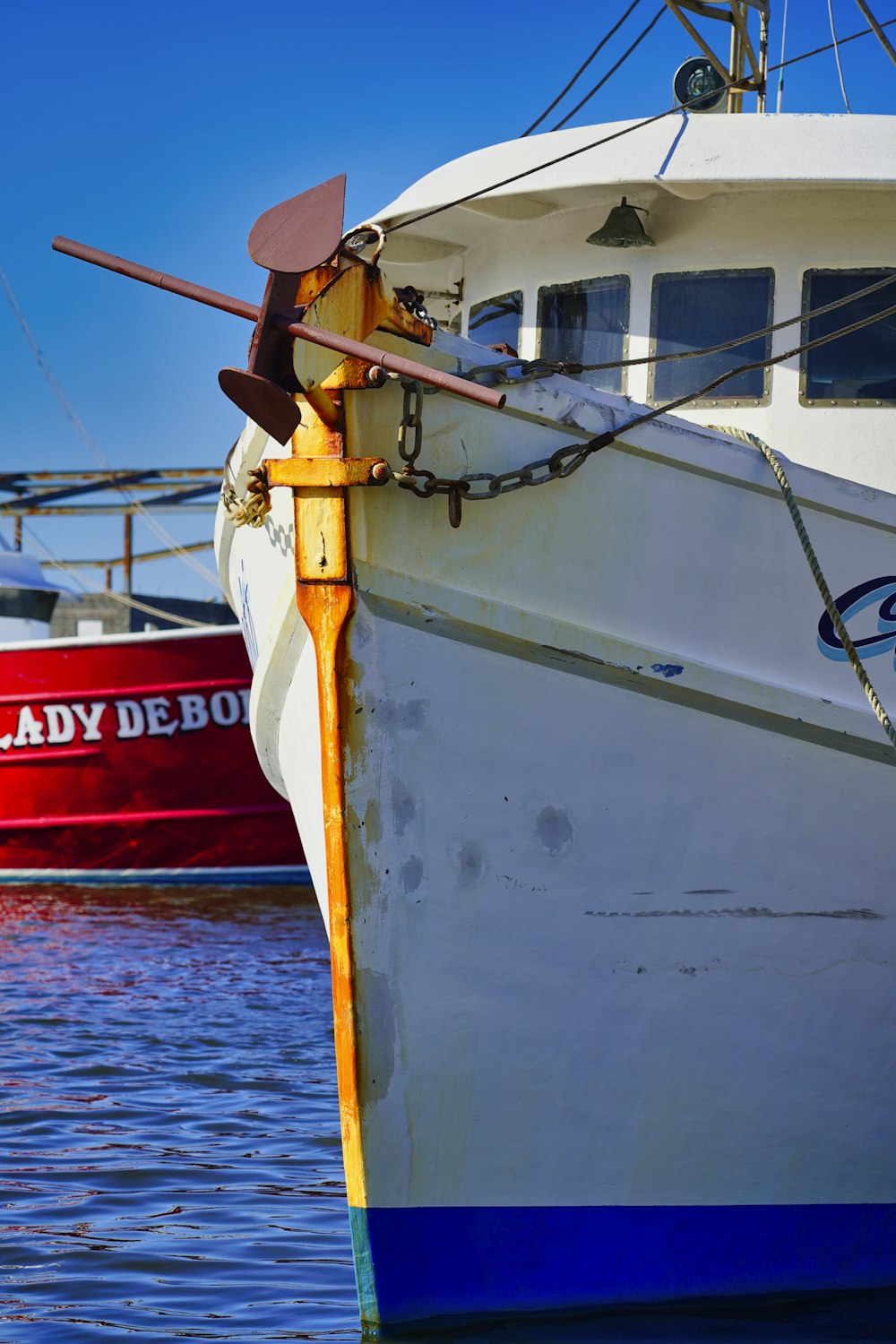 man in yellow shirt and brown pants wearing brown hat standing on white and red boat