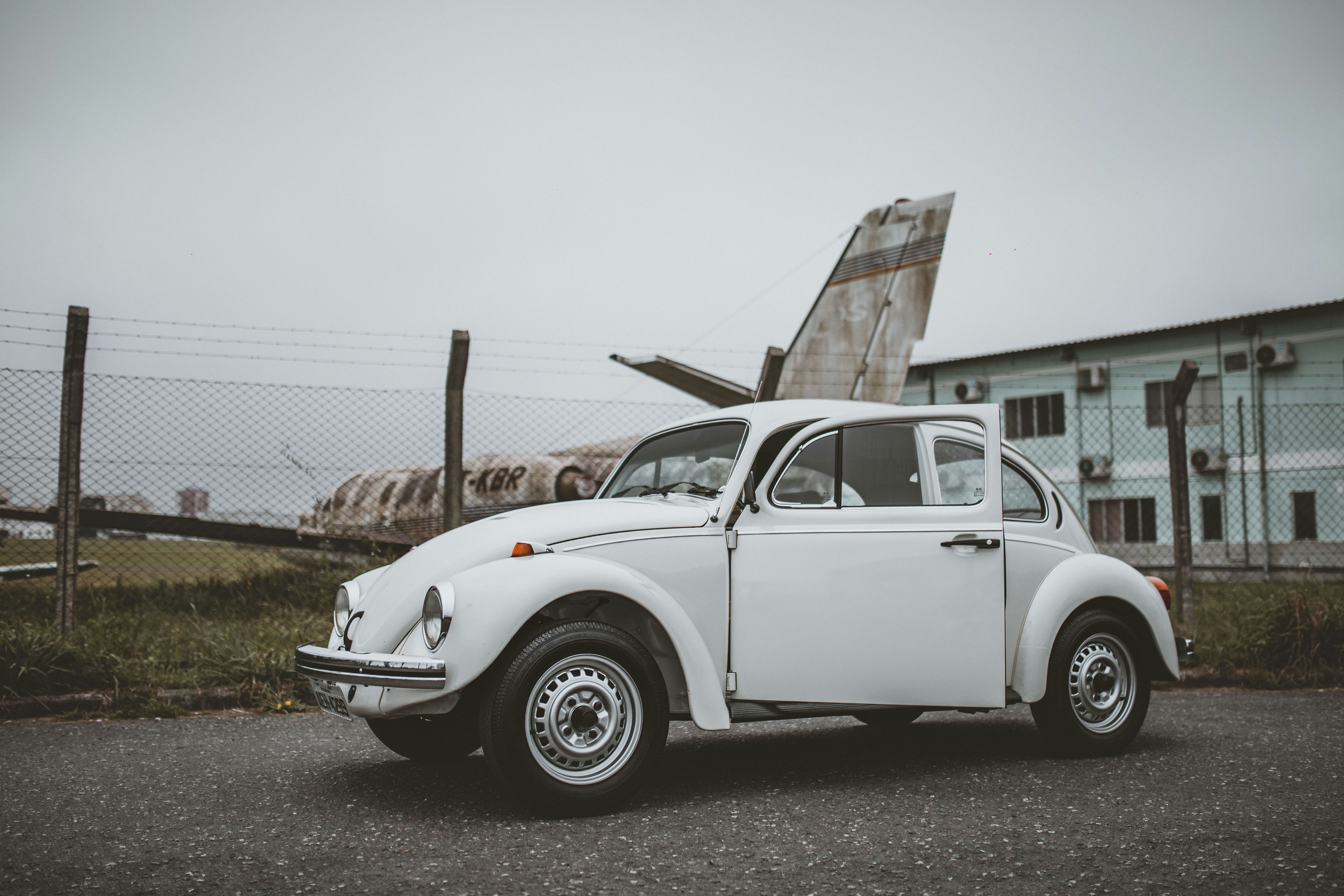 white classic car parked on gray concrete pavement during daytime