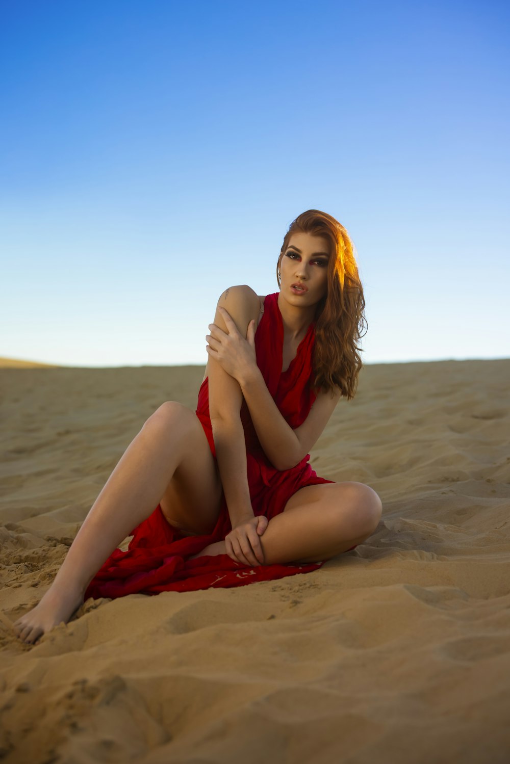woman in black tank top sitting on brown sand during daytime