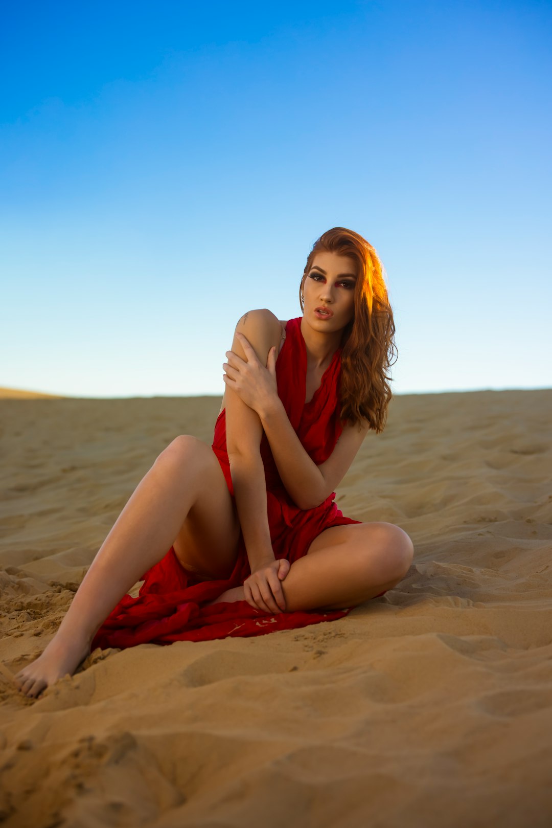 woman in black tank top sitting on brown sand during daytime