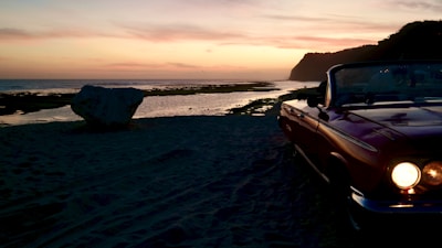 A convertible car on a sunny beach.