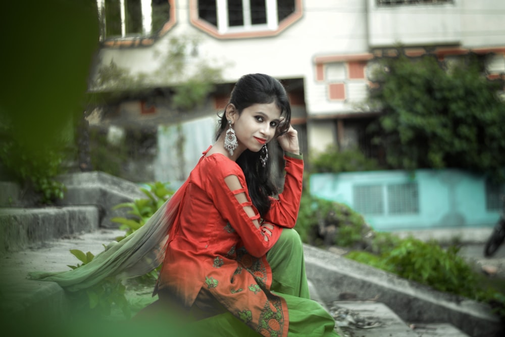 woman in red and green sari sitting on gray concrete bench during daytime