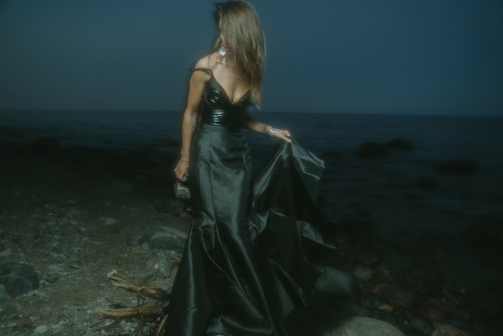 woman in black sleeveless dress standing on beach shore during daytime