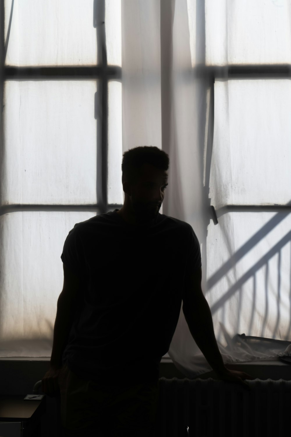 man in black polo shirt standing near white window curtain